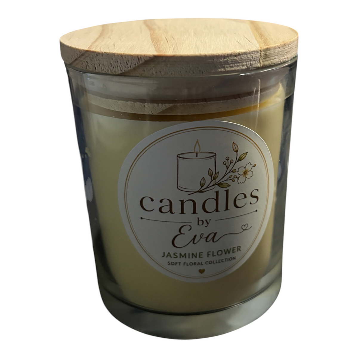 A jar candle with a light wood lid and cream-colored wax inside a clear glass container, featuring a round white label that reads 'candles by Eva' and 'JASMINE FLOWER'.